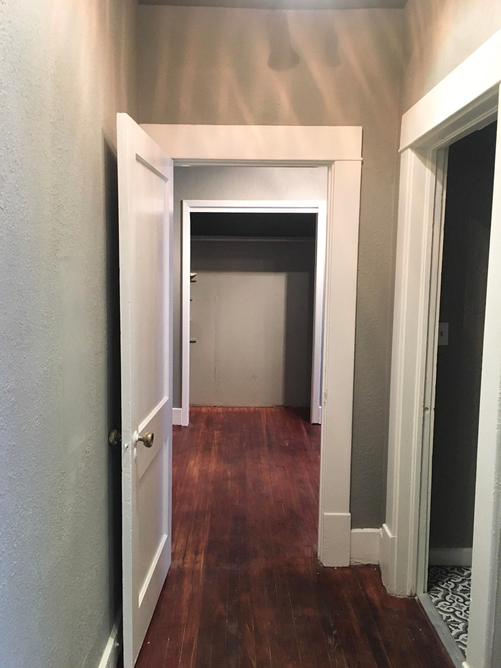 a hallway with wood floors and a white door