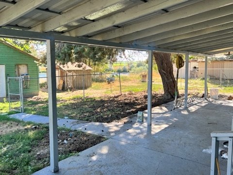 a patio with a tree and a chain link fence