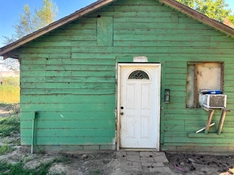 a small green building with a white door