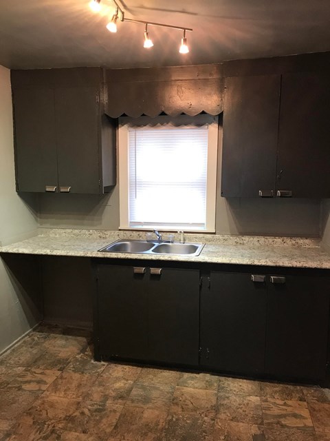 a kitchen with dark cabinets and a window and a sink