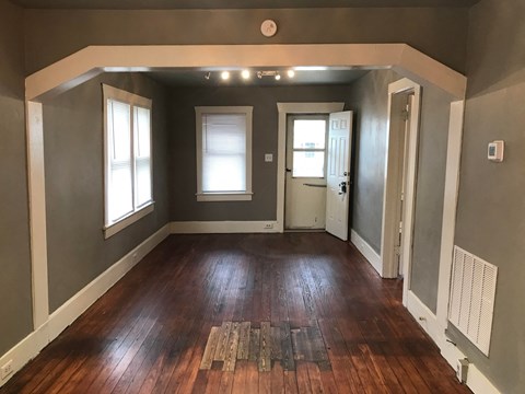 a living room with a hard wood floor and grey walls