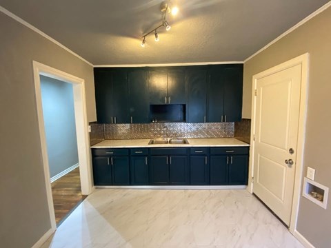 A kitchen with dark cabinets and a white door.