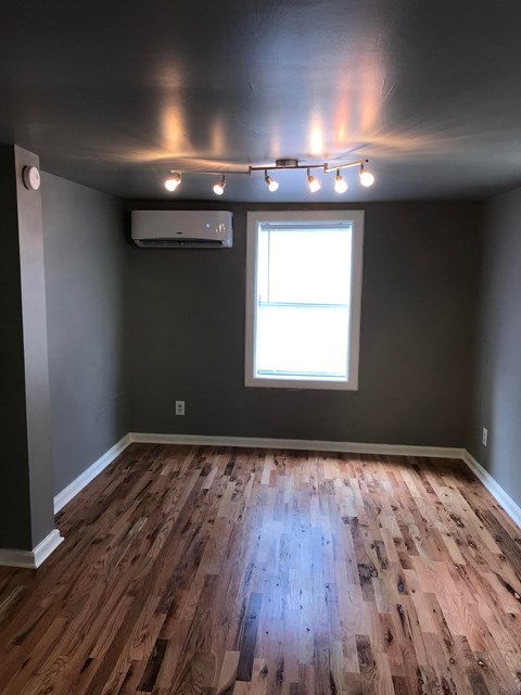a living room with wooden floors and gray walls and a window