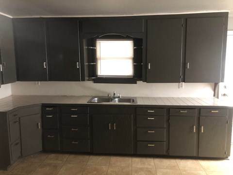an empty kitchen with black cabinets and a sink