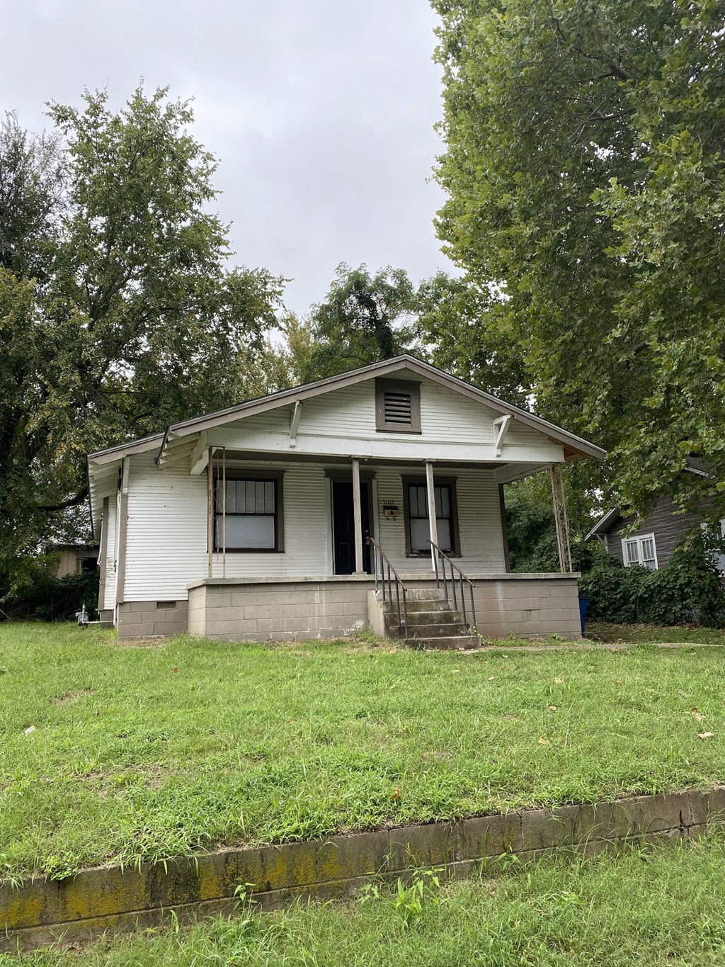 a small white house with a yard and trees