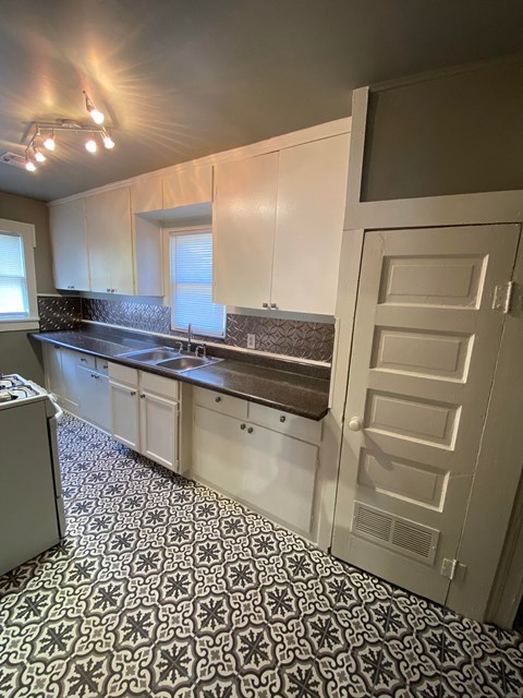 an empty kitchen with white cabinets and a white door