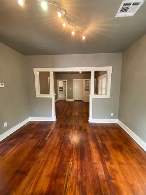 an empty living room with wooden floors and gray walls