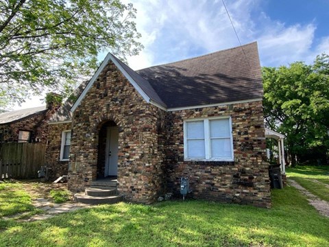 a small brick house with a front yard and grass