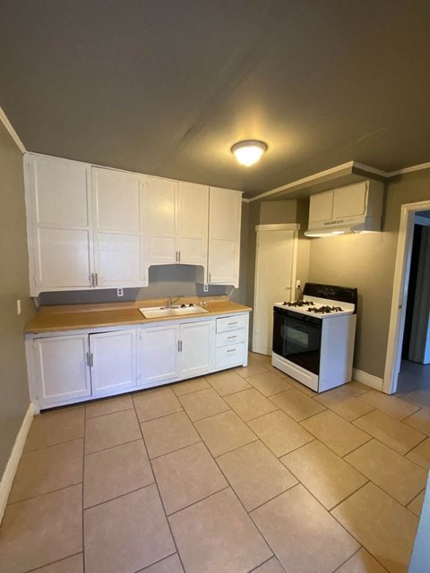 a kitchen with white cabinets and a stove and a sink