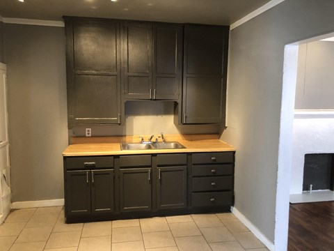 an empty kitchen with dark cabinets and a sink