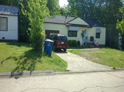 A white house with a yellow roof and a blue trash can.