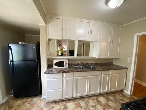 A kitchen with white cabinets and a black refrigerator.