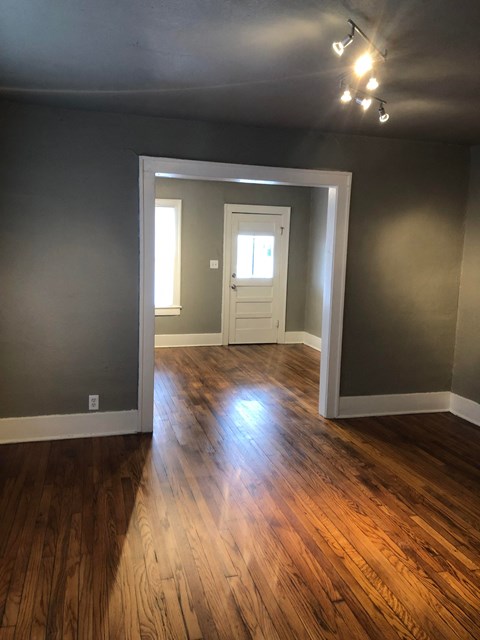an empty living room with a hard wood floor and gray walls