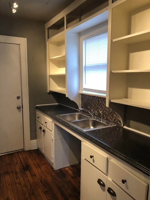 a kitchen with white cabinets and a sink and a window
