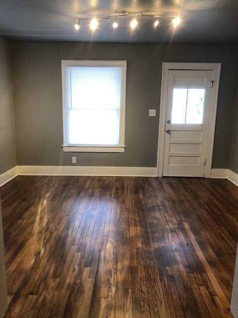 a living room with a hard wood floor and a door