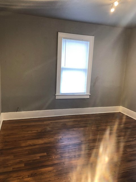 an empty room with a window and wooden floors