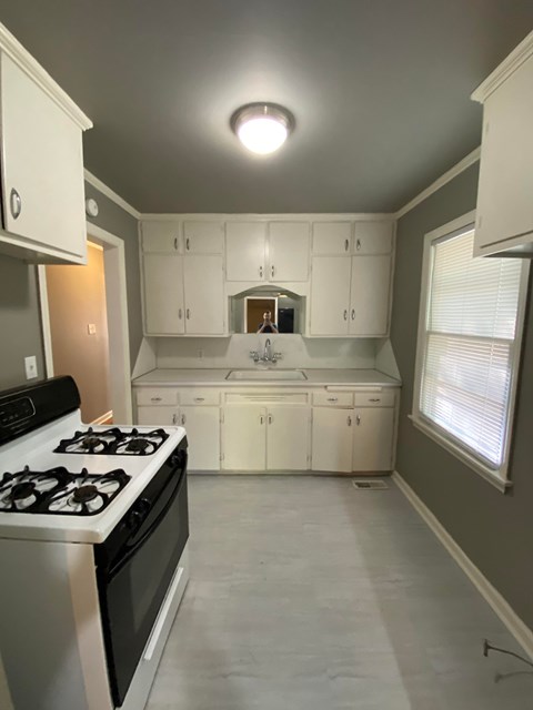 A kitchen with white cabinets and a black stove top oven.