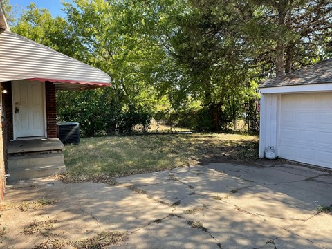 a backyard with a driveway and a garage and trees