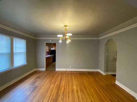 an empty living room with wood flooring and a chandelier