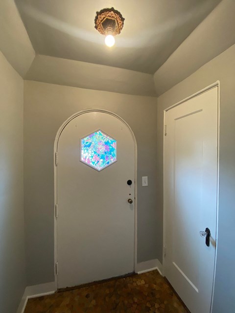 a hallway with an arched door and a stained glass window on the ceiling