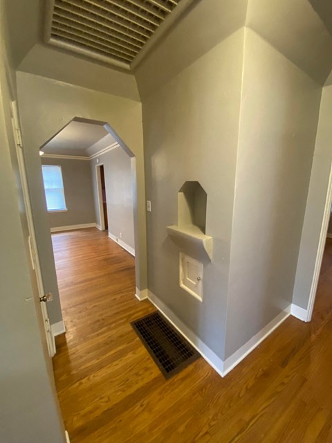 a hallway with wood flooring and white walls and a small shelf on the wall