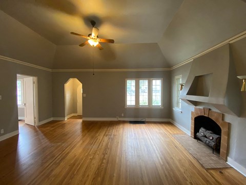 an empty living room with a ceiling fan and a fireplace