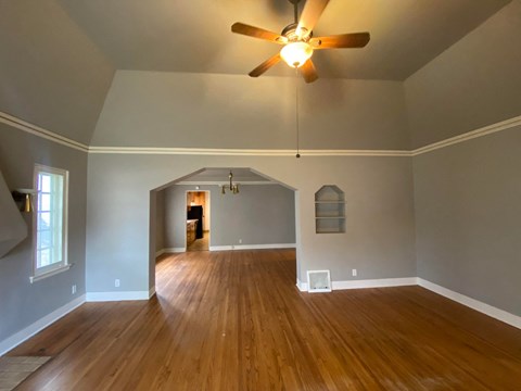 an empty living room with a ceiling fan and wood floors