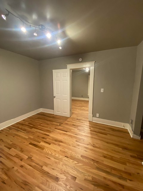 a living room with wooden floors and grey walls and a white door