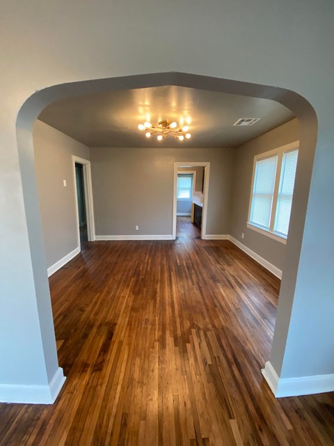 an empty living room with wooden floors and a ceiling fan