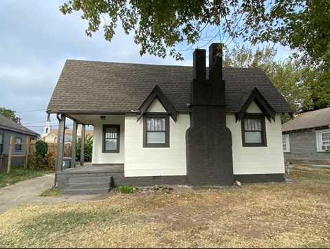 a small white house with a black roof and a porch