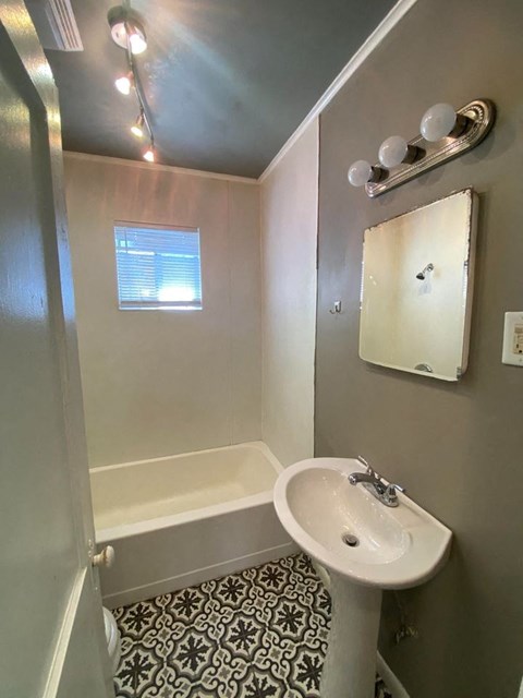 A bathroom with a sink, mirror, and bathtub.