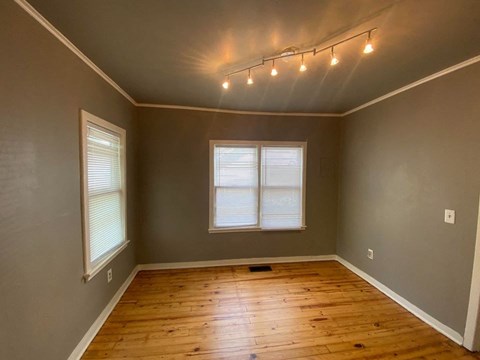 A room with wooden floors and a window with blinds.