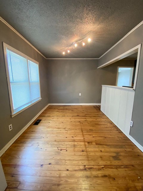A room with wooden floors and a window with blinds.