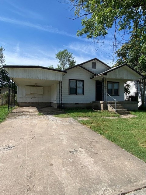 A white house with a concrete driveway in front.