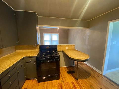 A kitchen with a black stove top oven and a counter top with a window in the background.