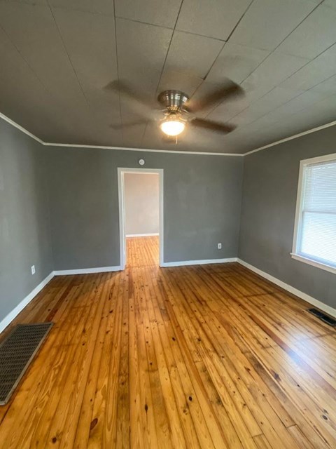 A room with wooden floors and a ceiling fan.
