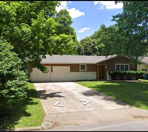 a house with a driveway and a lawn and trees