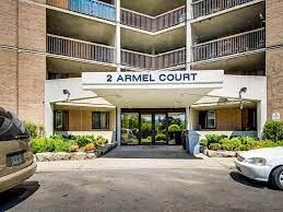 the front entrance of an apartment building with cars parked in front