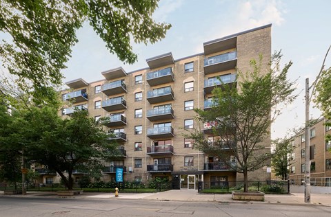A large apartment building with balconies and trees in front.