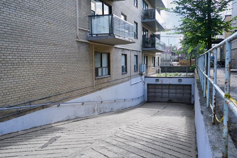 A view of a courtyard between two buildings with a metal railing on the right side.
