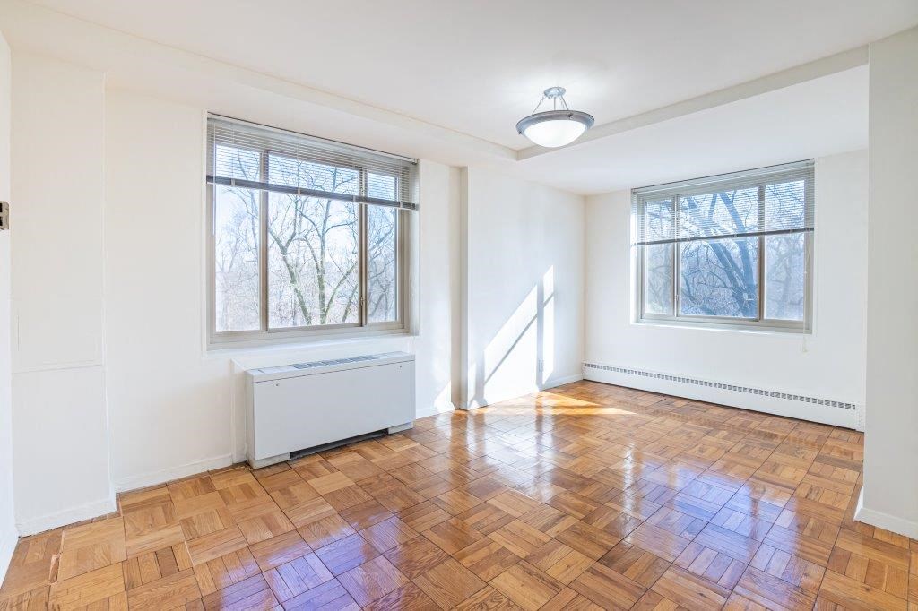 an empty living room with a hard wood floor and two windows