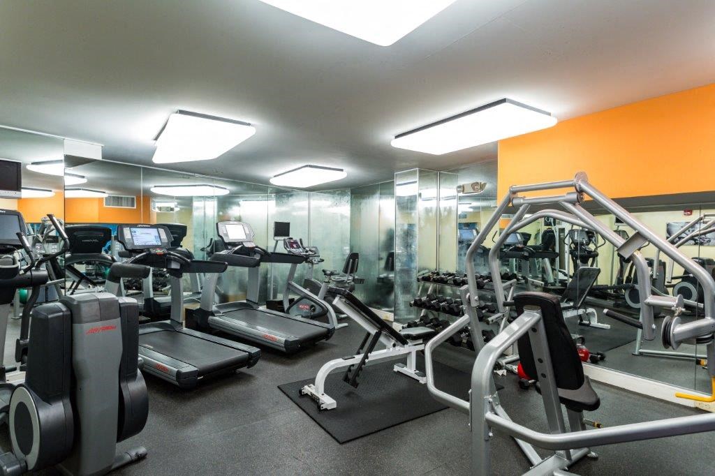 a gym with cardio equipment and mirrors in a building