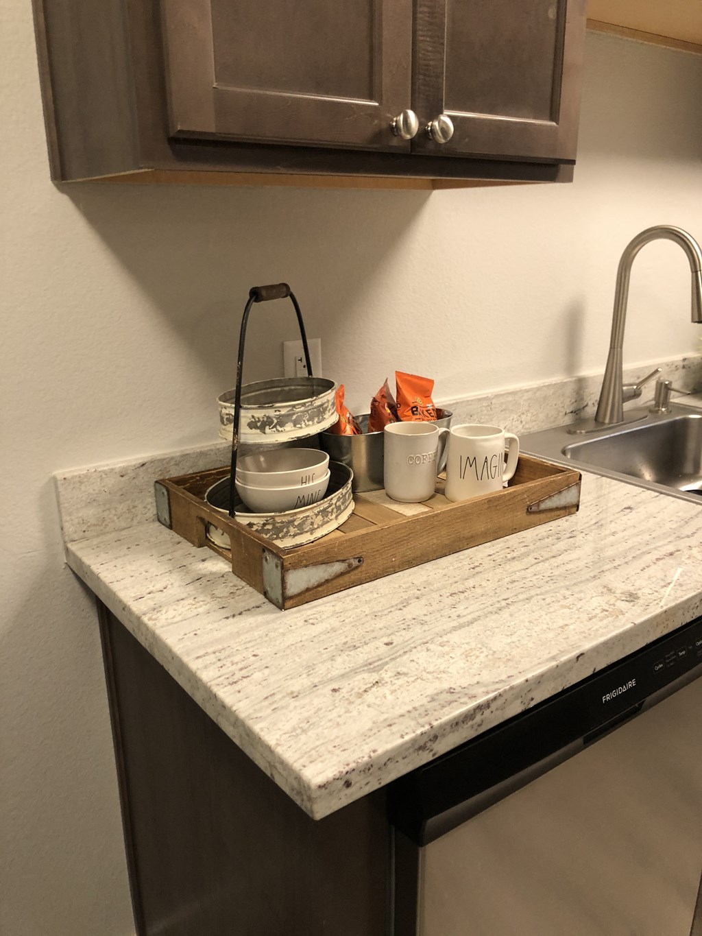 a kitchen with a sink and a counter with plates and cups on it