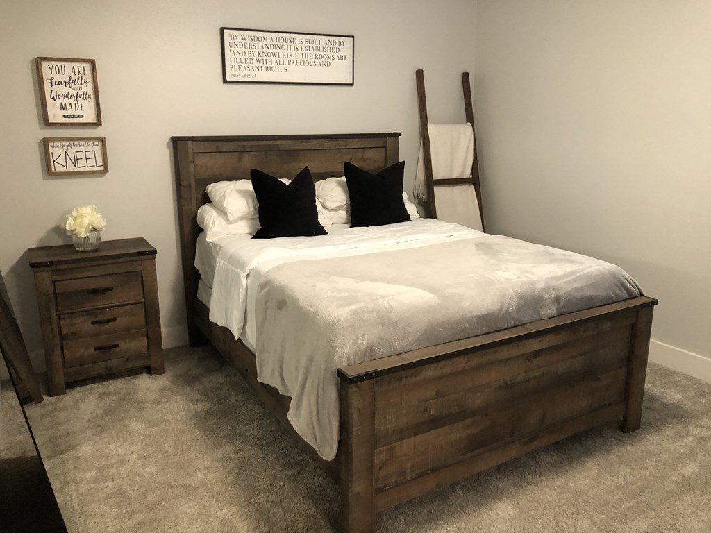 a bedroom with a bed with a white comforter and black pillows