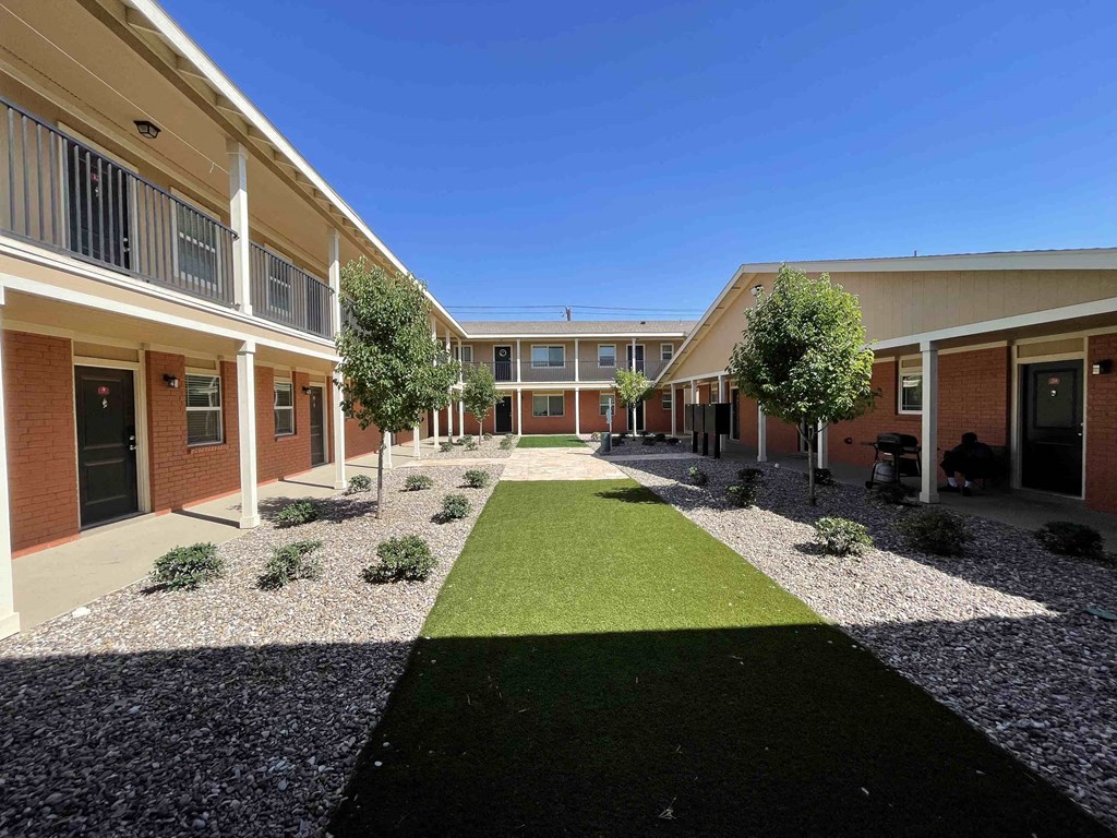 a courtyard in a building with green grass and trees