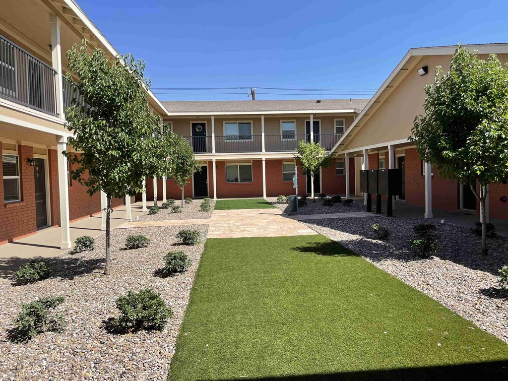 a courtyard in a building with green grass and trees