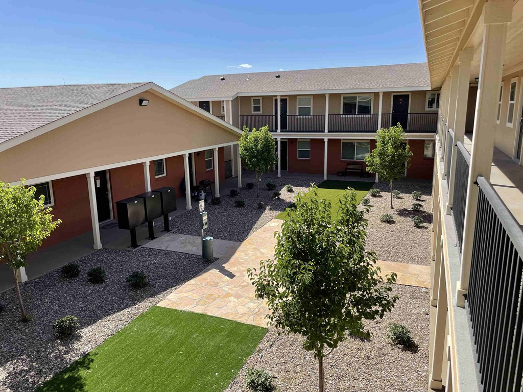 a view of the courtyard of an apartment building with grass and trees
