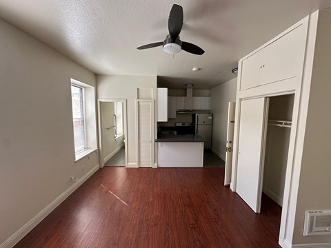 A room with a ceiling fan and wooden floors.
