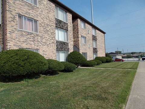 a brick apartment building with a sidewalk and green grass