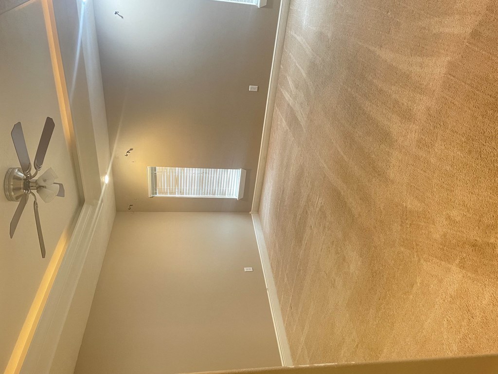 an empty room with a ceiling fan and a window